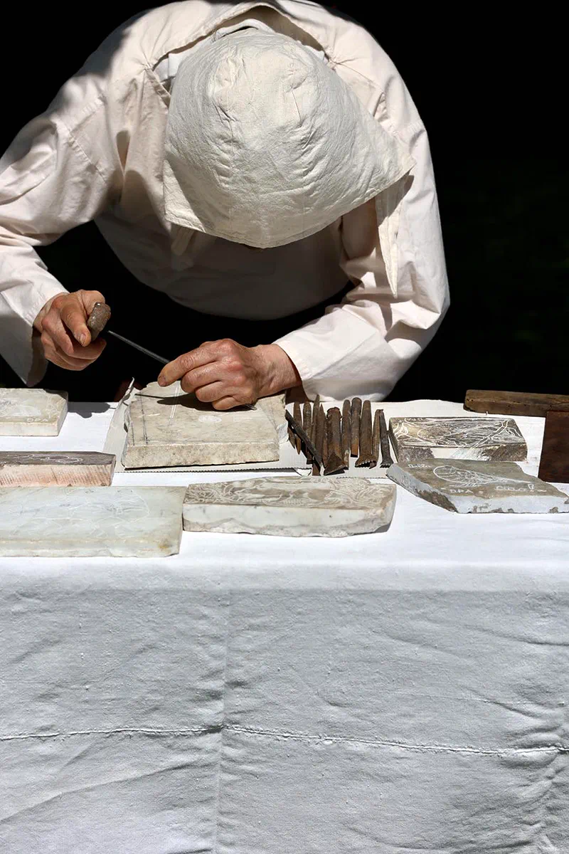 Lo scalpellino che incide una formella di marmo