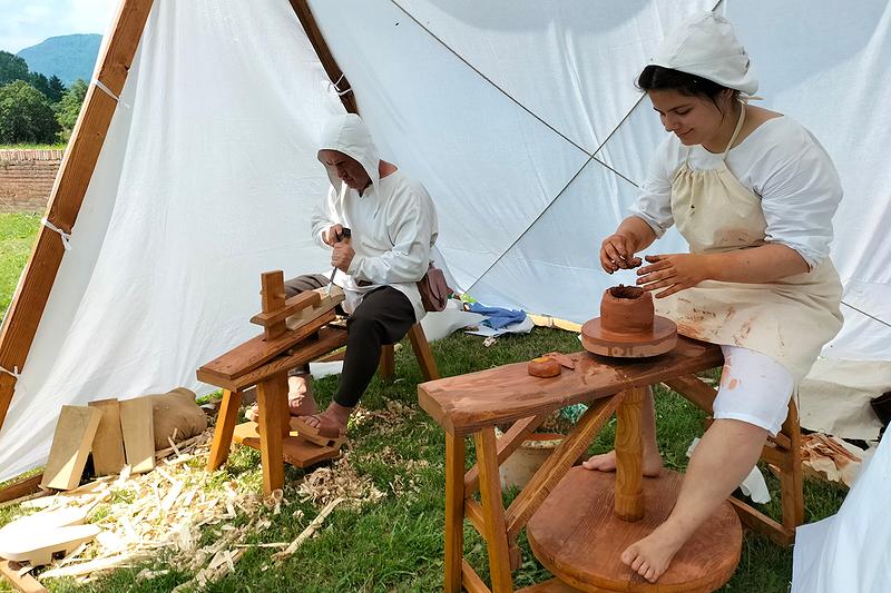 Vasaia che modella un vaso su tornio a pedale. A sinistra lo zoccolaro